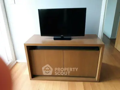 Modern wooden TV stand with flat-screen television in a stylish living room setting.