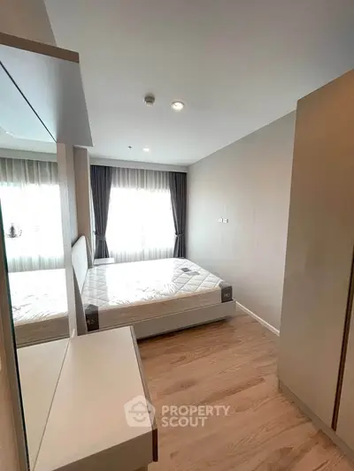 Modern bedroom with natural light and minimalist design, featuring a comfortable bed and wooden flooring.