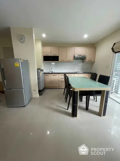 Modern kitchen with dining area, featuring sleek cabinetry and stainless steel appliances.