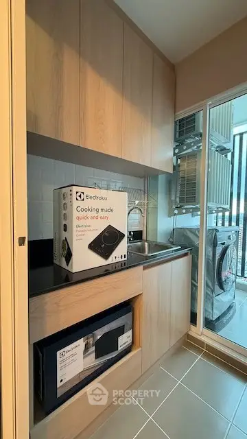 Modern kitchen with sleek cabinetry and appliances, featuring a compact Electrolux cooking unit and washing machine.