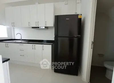 Modern kitchen with sleek black fridge and white cabinetry, perfect for contemporary living.