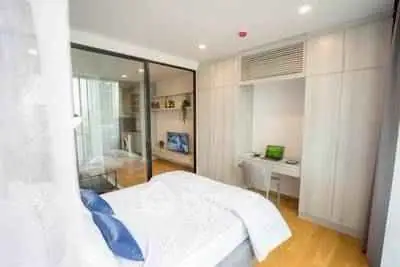 Modern bedroom with built-in wardrobe and study area, featuring sleek design and natural light.
