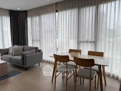 Modern living room with floor-to-ceiling windows and stylish dining area in a high-rise apartment.