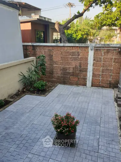 Charming small garden patio with potted plants and brick wall, perfect for outdoor relaxation.