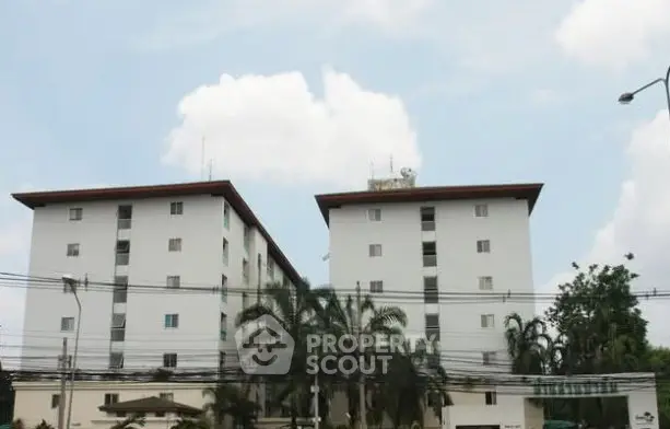 Modern apartment building with lush greenery and clear sky view.