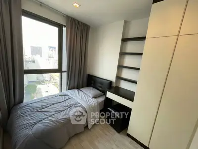 Modern bedroom with city view, featuring sleek furniture and ample natural light.