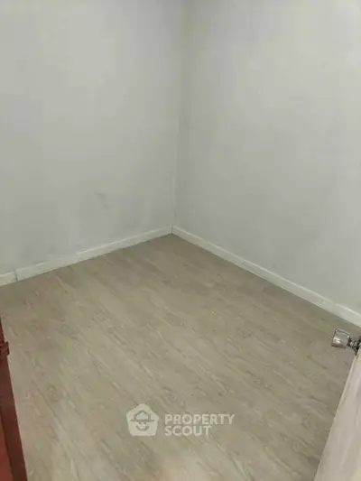 Minimalist empty room with light wood flooring, perfect for customization.