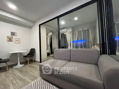 Modern living room with sleek gray sofa and glass partition, featuring stylish decor and cozy ambiance.