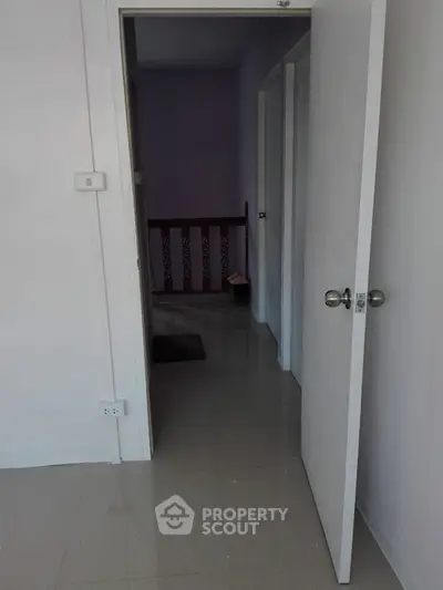 Interior hallway with open door leading to a corridor, showcasing minimalist design.