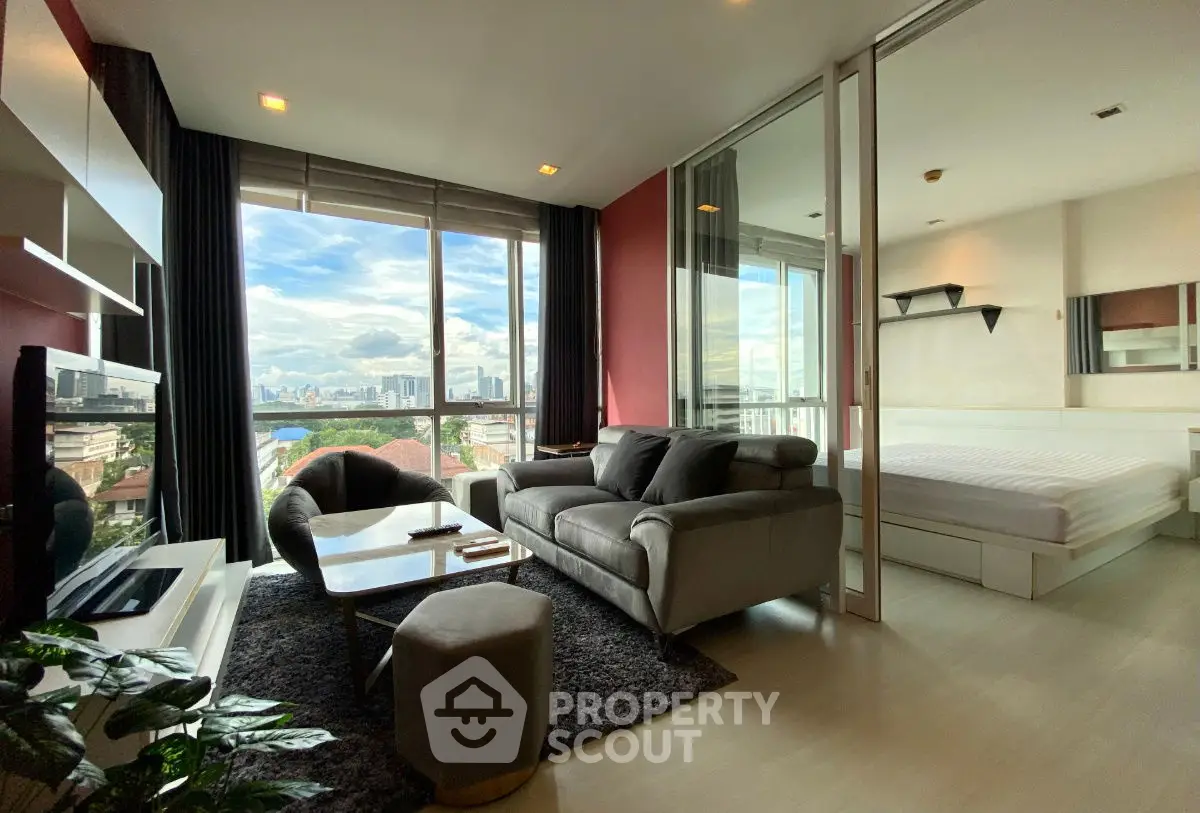Modern living room with city view, cozy sofa, and stylish decor in a high-rise apartment.