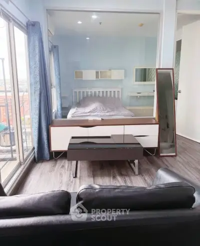 Modern bedroom with glass partition and balcony view, featuring sleek furniture and stylish decor.