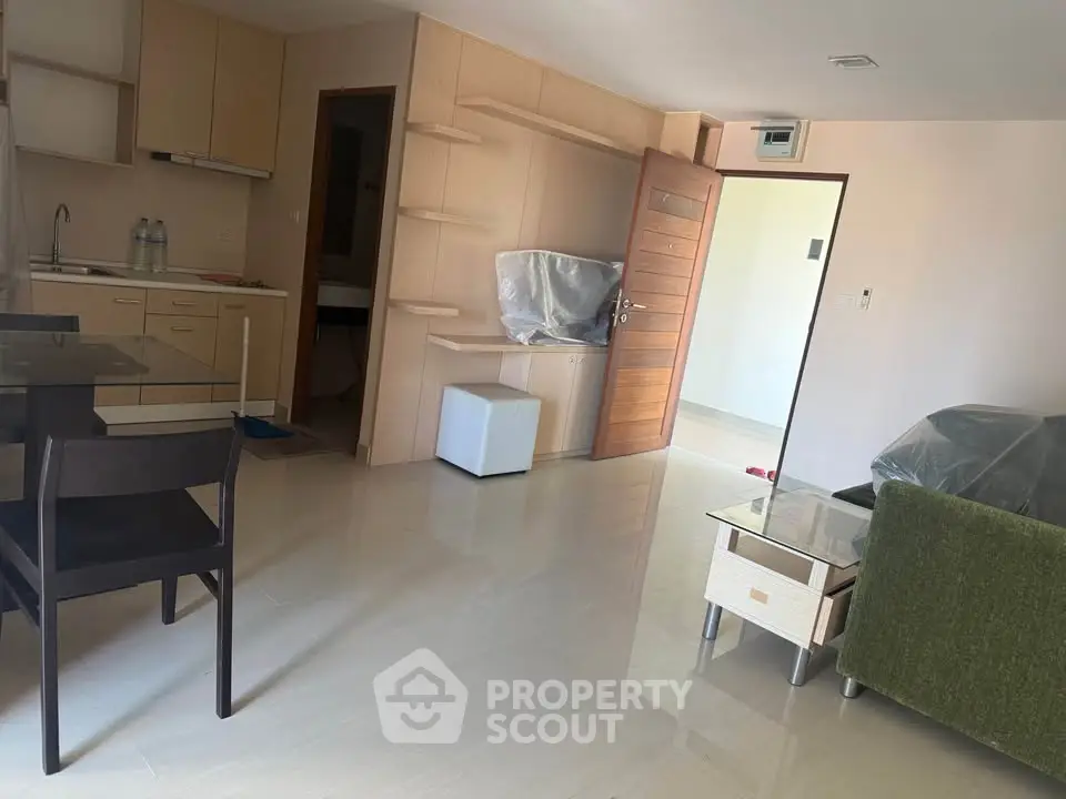 Modern apartment interior with open kitchen and living area, featuring sleek furniture and natural light.