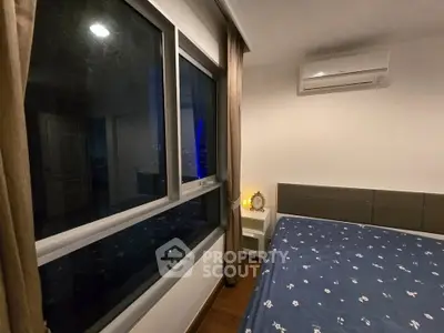 Cozy bedroom with large window and air conditioning unit, perfect for relaxation.
