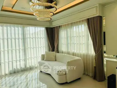 Luxurious living room with elegant chandelier and large windows with sheer curtains.