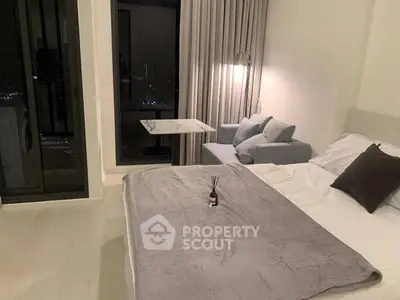 Modern bedroom with city view, cozy sofa, and elegant decor in a high-rise apartment.