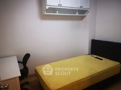 Cozy bedroom with single bed, desk, and wall-mounted storage in modern apartment.