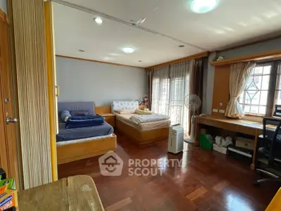 Spacious bedroom with wooden flooring and ample natural light