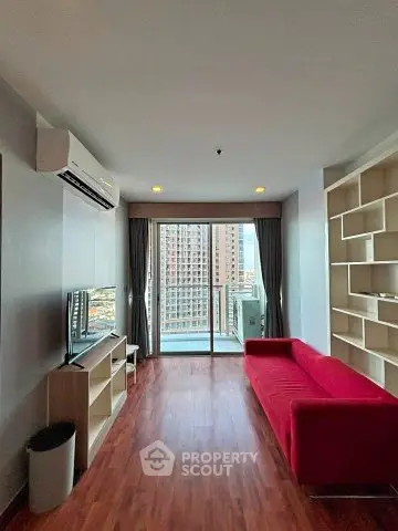 Modern living room with red sofa and city view balcony in high-rise apartment.