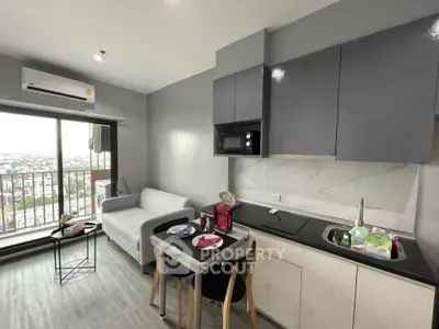 Modern apartment with open kitchen and balcony view, featuring sleek cabinetry and cozy dining area.