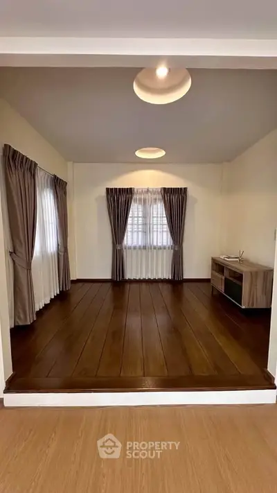 Spacious living room with elegant curtains and wooden flooring