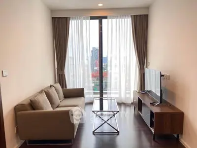 Modern living room with city view, featuring sleek furniture and floor-to-ceiling windows.