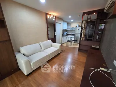 Spacious living room with modern kitchen in open layout, featuring elegant wooden flooring and stylish furniture.
