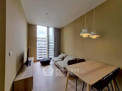 Modern living room with stylish furniture and natural light, featuring a cozy sofa and dining area.