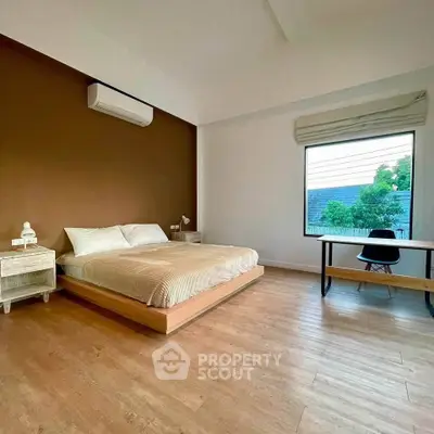 Spacious bedroom with modern decor and large window offering natural light.