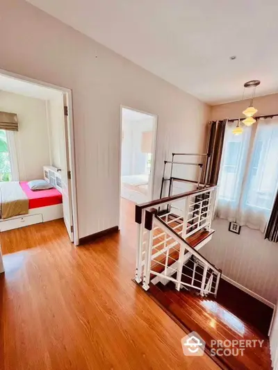 Bright and airy staircase with wooden flooring leading to cozy bedrooms in modern home.