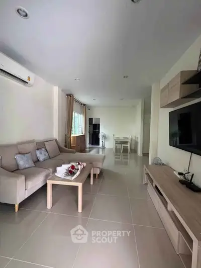 Spacious modern living room with elegant furniture and large TV, perfect for relaxation and entertainment.