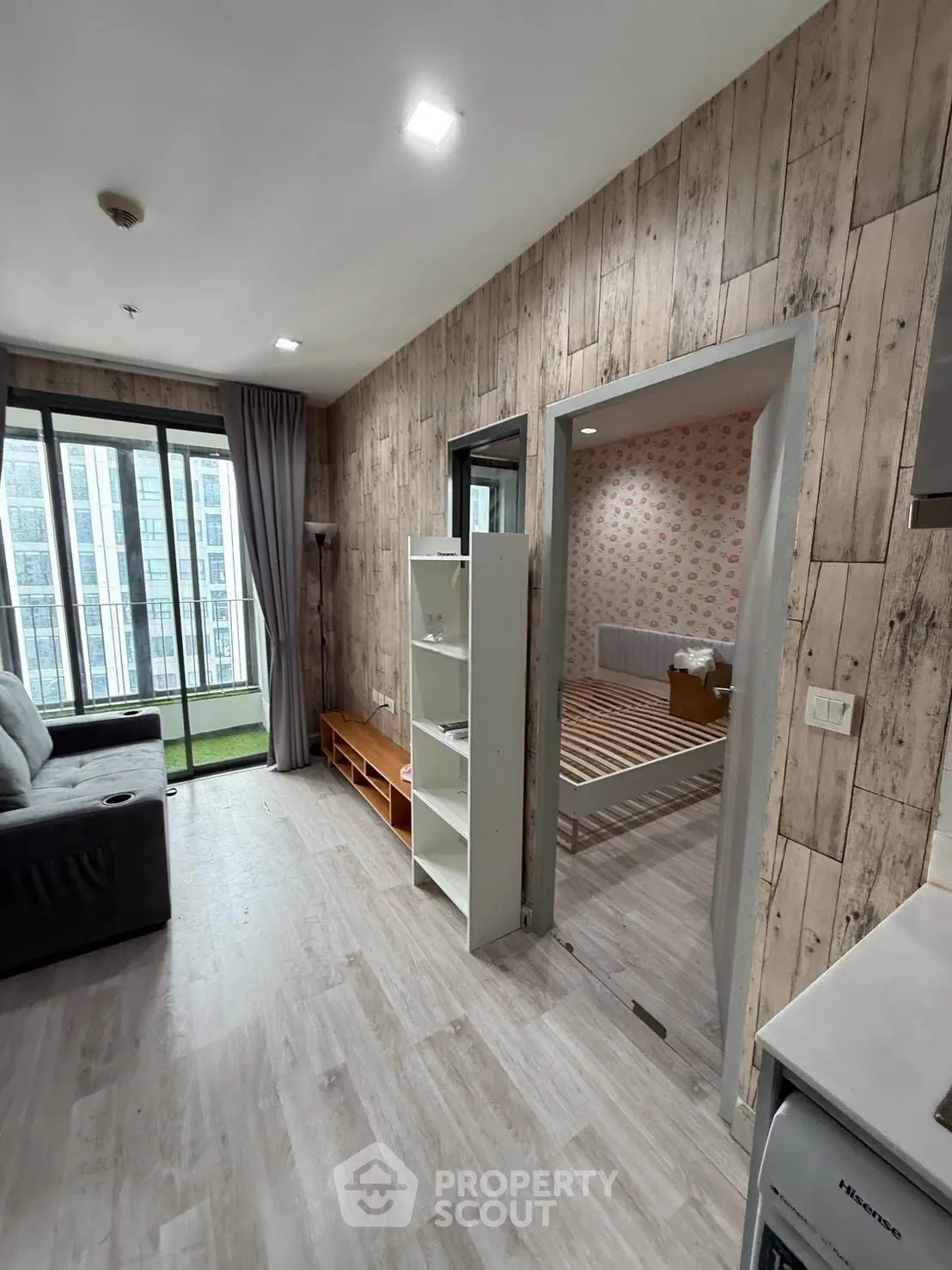 Modern apartment interior with wooden accents and large windows offering city views.