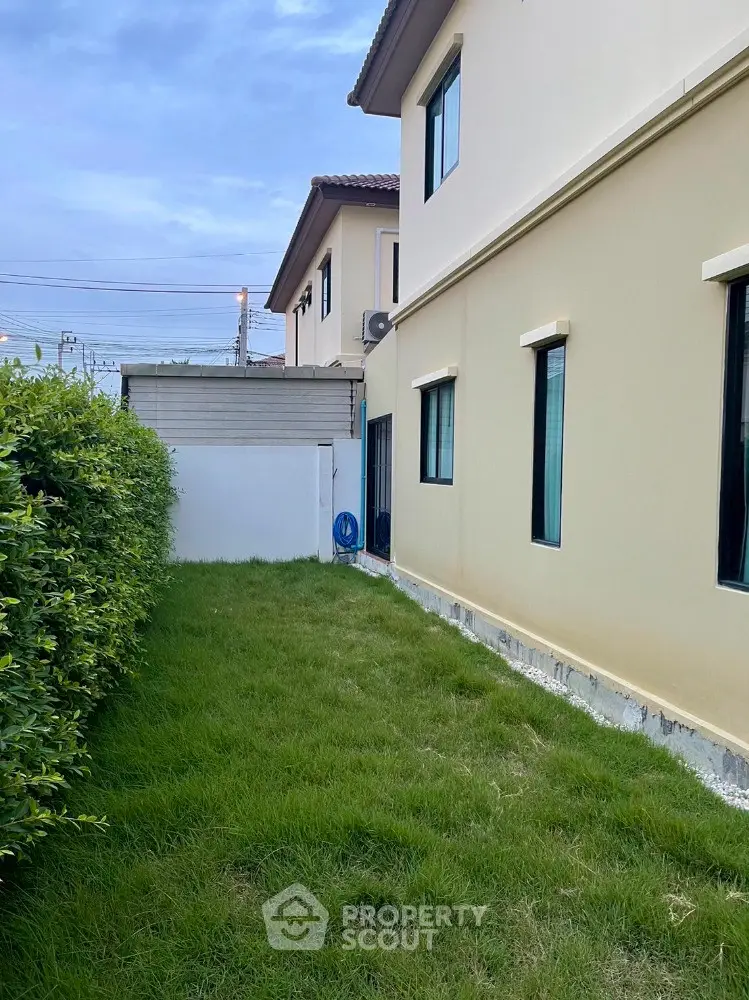 Charming side garden of a modern home with lush greenery and privacy fence.