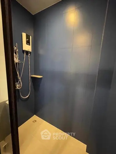 Modern bathroom shower area with sleek blue tiles and water heater.