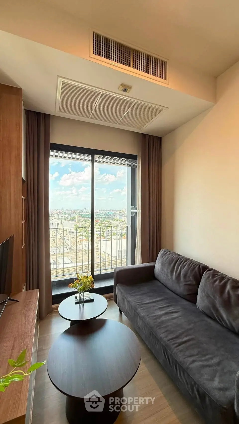 Stylish living room with a stunning city view from a high-rise balcony, featuring modern furniture and decor.
