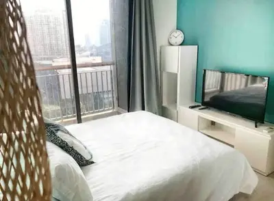 Modern bedroom with city view, featuring a cozy bed, TV, and stylish decor.