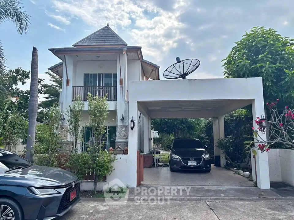 Charming two-story house with carport and lush greenery in a serene neighborhood.