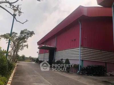 Spacious industrial warehouse with red exterior and ample driveway space.
