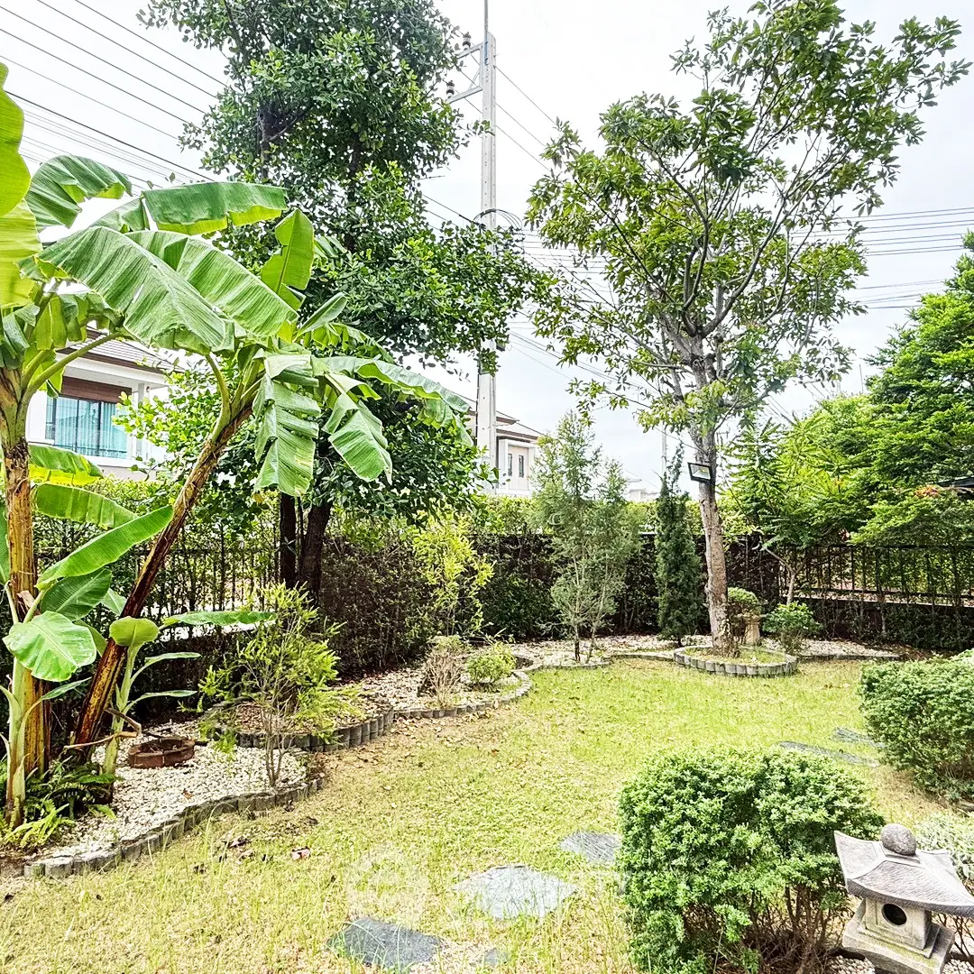 Charming garden with lush greenery and trees in a serene residential area.