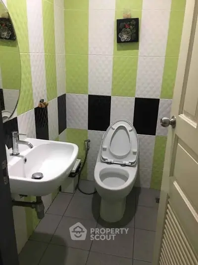 Modern bathroom with unique green and black tile design and sleek fixtures.