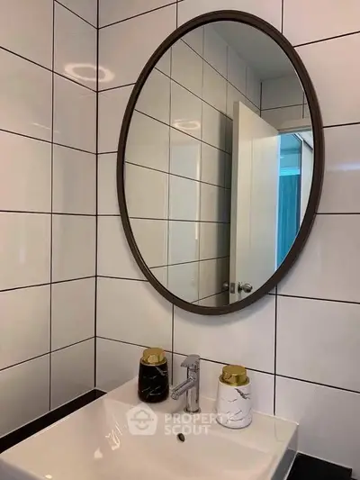 Modern bathroom with stylish oval mirror and sleek sink design.