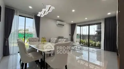 Spacious modern dining room with elegant furniture and large windows offering garden views.