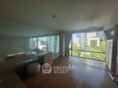 Spacious modern living room with large windows offering stunning city views and natural light.