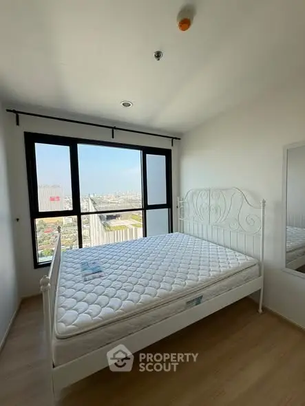 Bright bedroom with large window offering stunning city view, featuring a stylish metal bed frame and hardwood flooring.