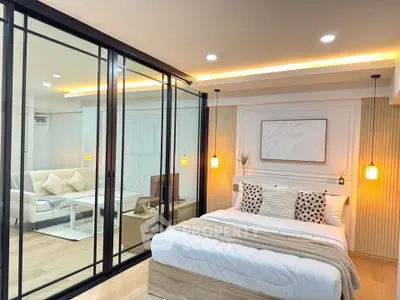 Modern studio apartment with glass partition and cozy bedroom decor.