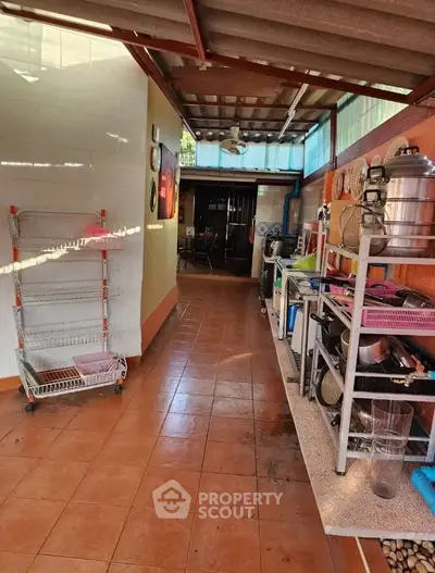 Spacious outdoor kitchen with tiled flooring and ample shelving.