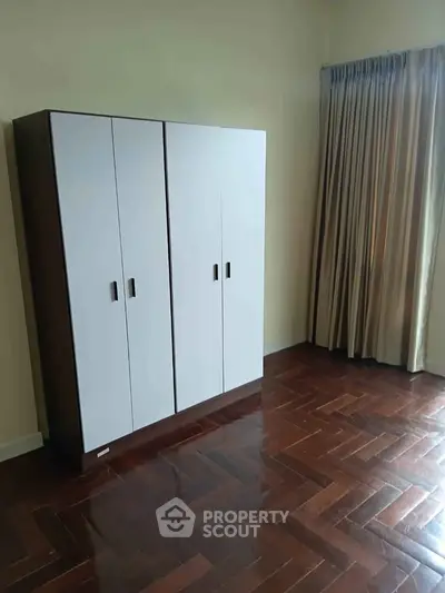 Spacious bedroom with elegant wooden wardrobe and polished hardwood floors.