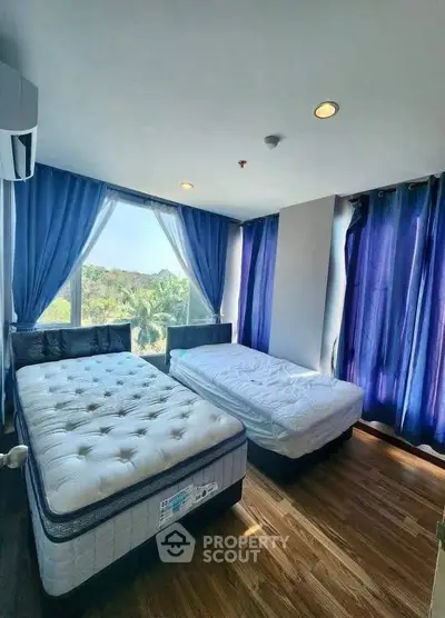 Spacious bedroom with two beds and large windows offering scenic views, perfect for relaxation.