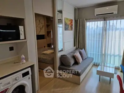 Modern compact living room with sofa, washing machine, and air conditioning in bright apartment.