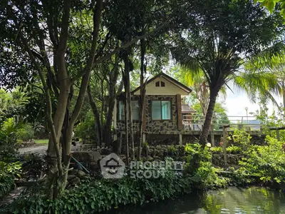Charming stone cottage surrounded by lush greenery and tranquil pond view.