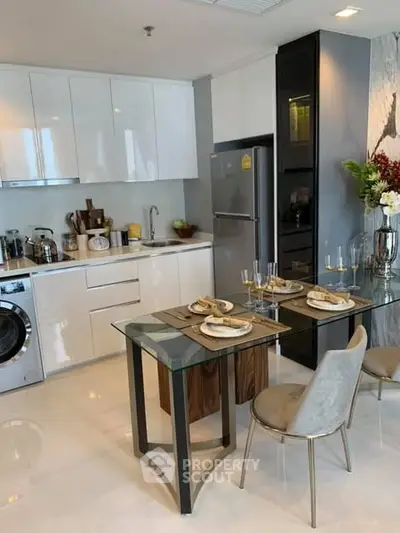 Modern kitchen with sleek cabinets, dining table, and appliances in a stylish apartment.